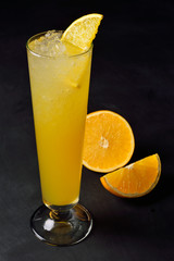Ice cold citrus cocktail in a hight glass. Dark background with copy space for a menu.