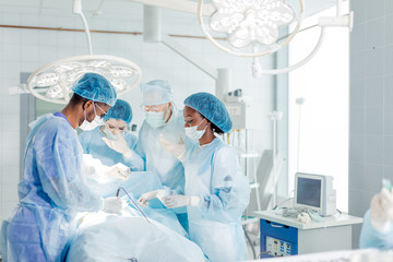awesome mixed race doctors, nurses conducting operation in the hospital