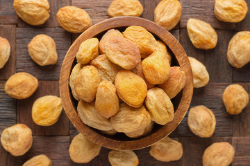 dried apricots with stone in wooden bowl, top view.