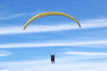 Tandem paraglider flying yellow wing