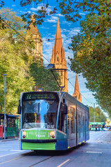 A Melbourne tram is traveling along Swanston Street near the Town Hall and St Paul's Cathedral