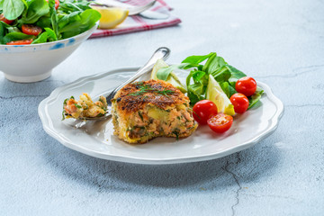 Homemade salmon fish cake with fresh leaf salad garnished with lemon