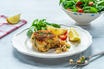 Homemade salmon fish cake with fresh leaf salad garnished with lemon