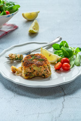 Homemade salmon fish cake with fresh leaf salad garnished with lemon