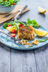 Homemade salmon fish cake with fresh leaf salad garnished with lemon