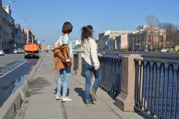 young ladies tourists in Saint Petersburg Russia have fun together on a sunny day, undress and jump of joy,