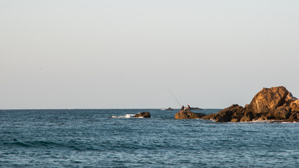 Fisherman fishing on a rock in ocean in Algeria