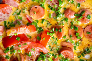 Omelette with tomato, onion and sausage on frying pan
