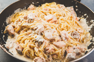 Pasta with salmon and creamy sauce on frying pan