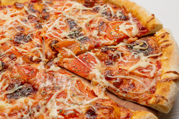 Italian pizza with mushrooms and tomatoes, pizza cut, close-up