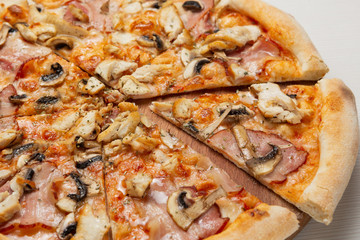 Italian pizza with mushrooms and ham slices, pizza cut, close-up