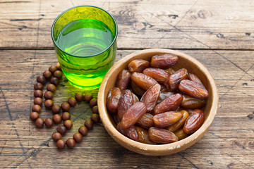 Dried dates fruits and a glass of water on a wooden table. Traditional fast breaking, Muslims evening meal during holy Ramadan