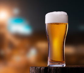 Glass of light beer on wooden table in cafe or restaurant with street view