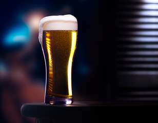 Glass of light beer on wooden table in cafe or restaurant with street view