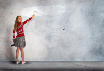 Little girl paints on the concrete wall. Background for your text or advertisement