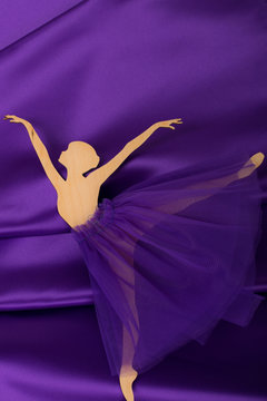 plywood ballerina figurine on purple fabric