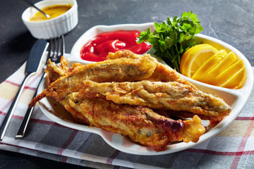 Fried in batter capelins on a plate, close-up