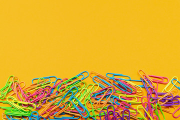 Obraz na płótnie Canvas multicolored paper clips lie on a yellow background, with copy space, a bunch of paper clips