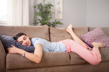 Tired funny young woman in summer everyday clothes stretches out and sleeps on sofa at home. Female...