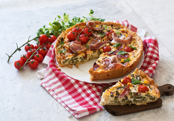 Tart or quiche with bacon, green beans, tomatoes and cheese on a red checkered tablecloth. French...
