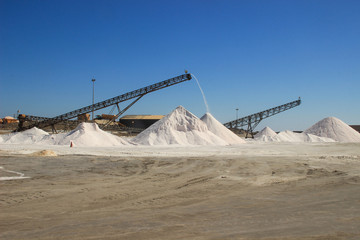 Walvis Bay, Namibia - April 25, 2015: Salt production at a factory from the Atlantic Ocean on the coast near Walvis Bay, Namibia. Mountains of salt.