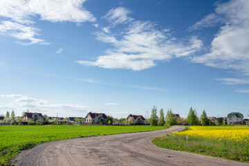 Village in countryside. Road to rural village along agricultural fields. Rural landscape. Agriculture
