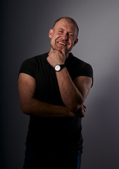 Exited fun smiling bald man holding the face in black casual shirt in fashion watches on grey background.