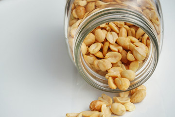 Roasted peanuts in the glass bottle on grey background for advertising. Clean food good taste ideas concept. Selective focus and free space for text.