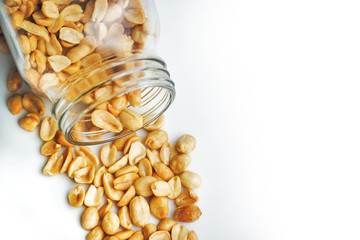 Roasted peanuts in the glass bottle on white background for advertising. Clean food good taste ideas concept. Selective focus and free space for text.