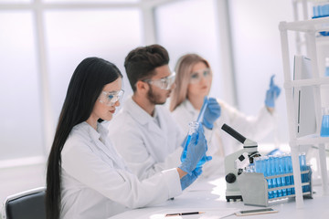 close up. woman scientist looking at the tube with liquid