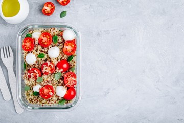 Vegetarian meal prep lunch box containers with quinoa, mozzarella cheese, tomatoes and basil.