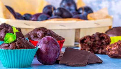 Czekoladowa mufinka ze śliwkami. Obok czekolada, a w tle śliwki. © Michał