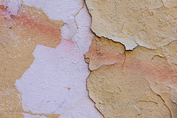 Natural background of old wall with shabby and peeling paint and plaster with cracks and stains of paint