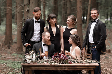 bride and groom sit at the table, set for a celebration in the woods