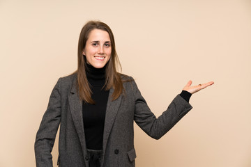 Young woman over isolated wall holding copyspace imaginary on the palm