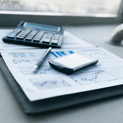 calculator, smartphone and financial documents on the businessm