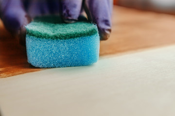 Manual wood coating stain. Wood impregnation. Handwork. With sponge. Impregnate wooden table with oil. In gloves