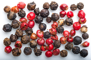 Red and black peppercorns on white background