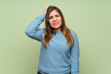 Fototapeta premium Young girl over green wall with an expression of frustration and not understanding