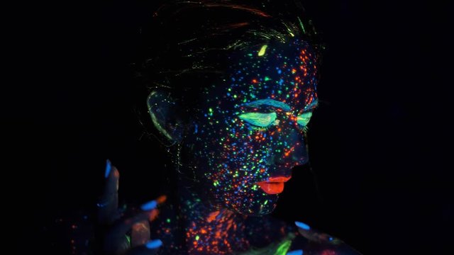 portrait of a girl in the neon light. face painted with glow in the dark paint.