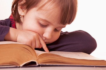 Little cute child girl watching a book as symbol of education and knowledge