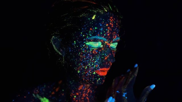 glow paint on the girl's face. Portrait of a beautiful young woman with glowing paint on her face.