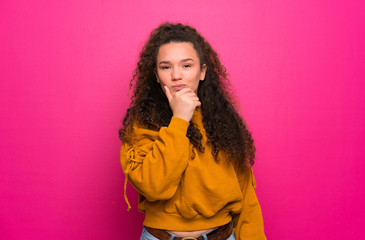 Teenager girl over pink wall thinking