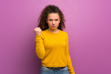 Teenager girl over purple wall with angry gesture