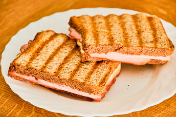 Toast  with ham and cheese on white plate
