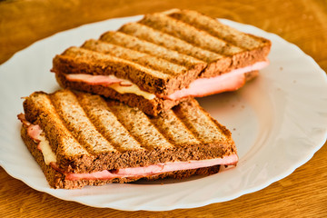 Toast  with ham and cheese on white plate