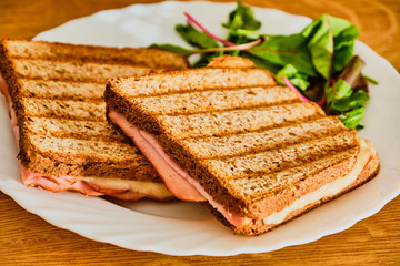 Toast with ham and cheese on white plate