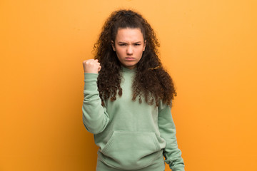 Teenager girl over ocher wall with angry gesture