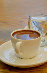 cup of Turkish coffee with a glass of water on wooden table