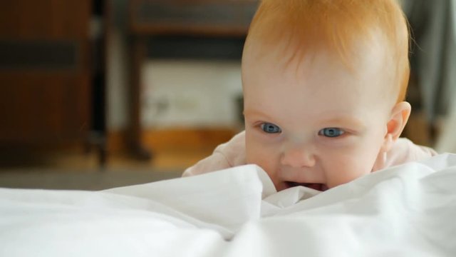Little readhead girl iclimbs to sofa with pillows at home
